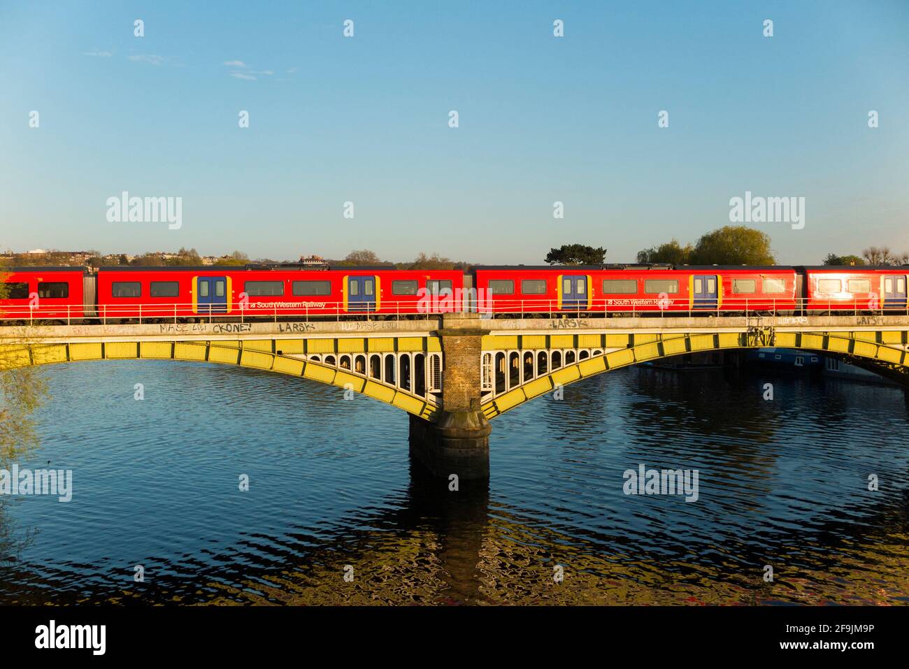 South Western treno ferroviario che attraversa il Tamigi vicino a Richmond, visto dal ponte di Twickenham al tramonto con cielo blu e sole / cielo blu e soleggiato. Richmond sul Tamigi. UK England (123) Foto Stock