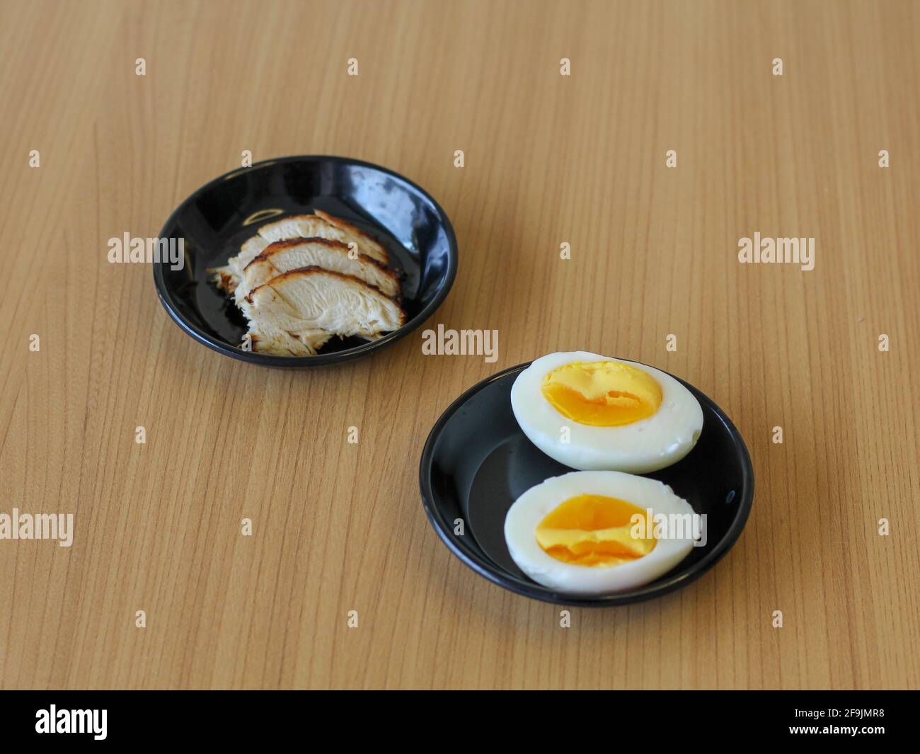 Ingredienti ricette giapponesi. Pollo affettato e uovo bollito su piatto nero Foto Stock