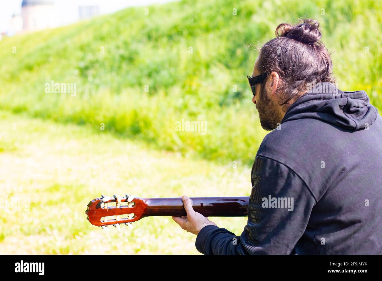 Uomo hippy con barba e occhiali che suonano la chitarra all'aperto l'erba Foto Stock