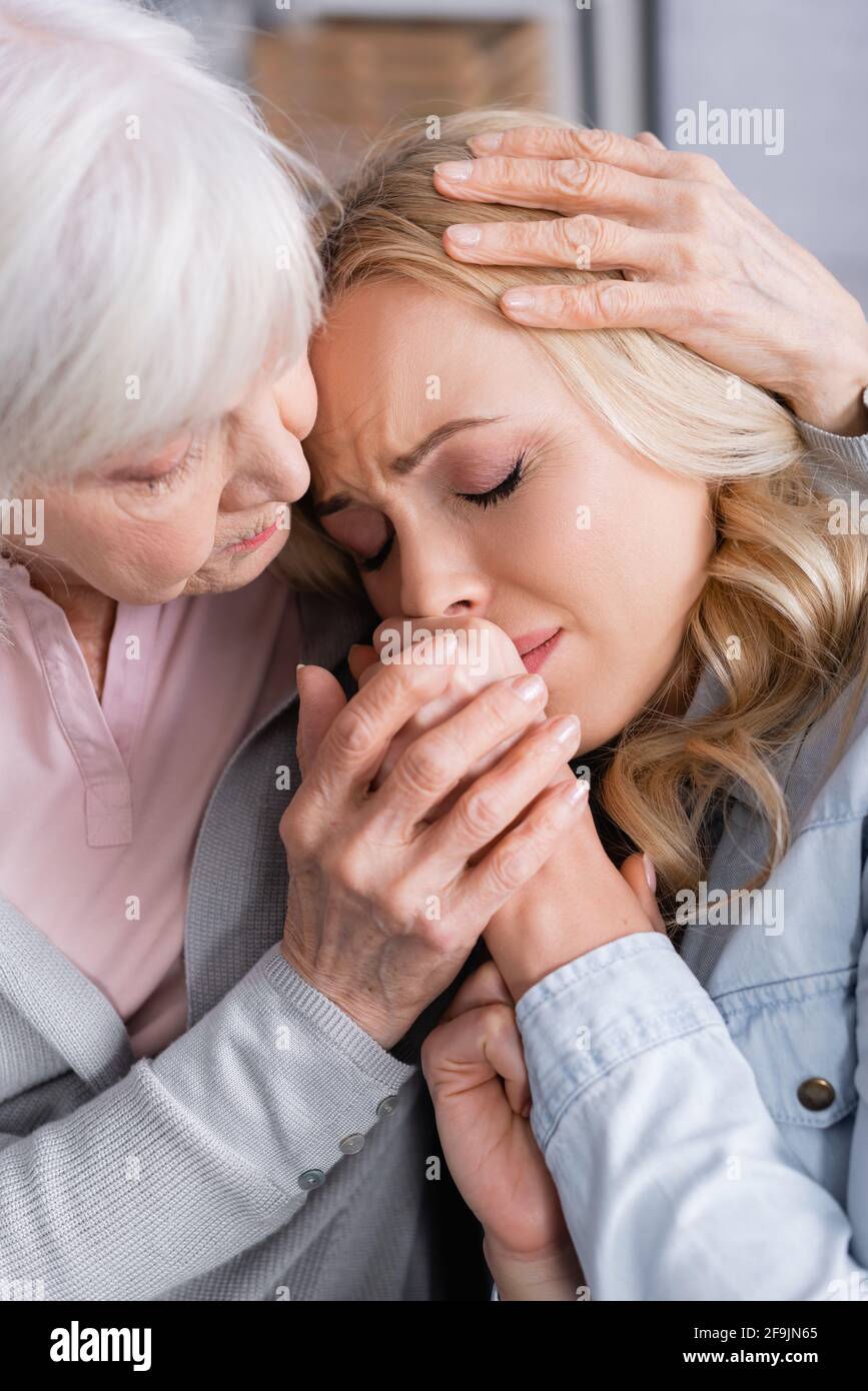 Donna anziana abbracciando e calmando sconvolto figlia Foto Stock