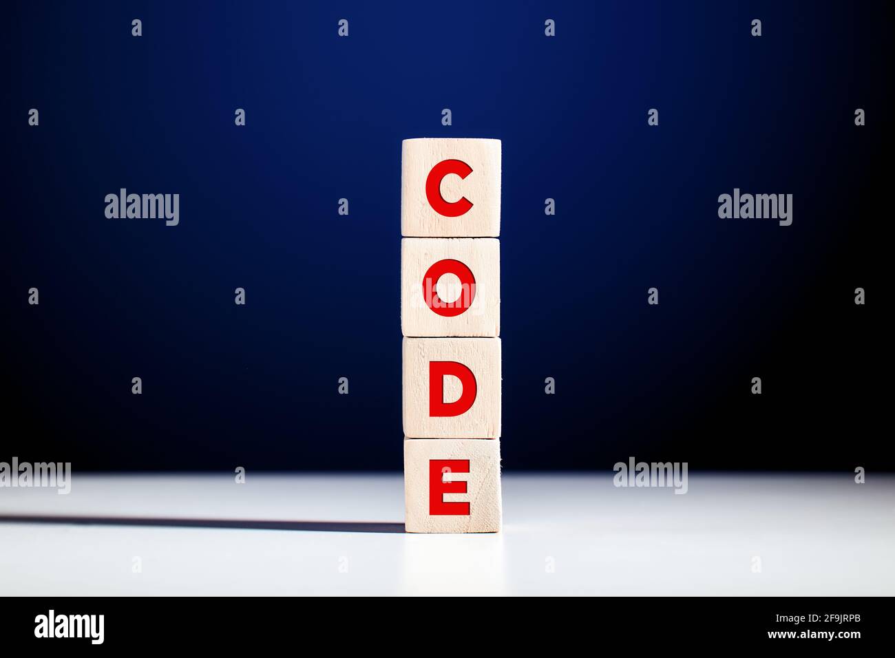 La parola codice scritto su cubi di legno a più livelli su sfondo blu. Foto Stock