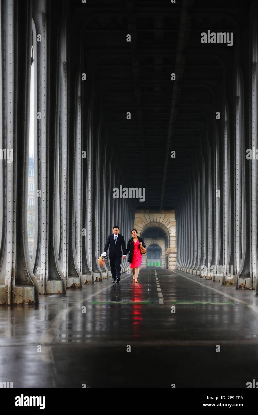 Parigi, Frankreich verliebtes Pärchen spaziert bei Regenwetter unter der Brücke Bir Hakeim und spiegelt sich im nassen Asphalt der Straßen von Paris Foto Stock