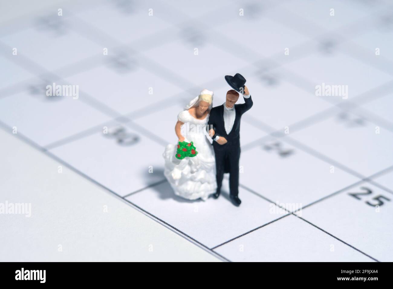 Matrimonio matrimonio giorno, calendario data celebrazione concetto miniatura persone giocattolo fotografia. Sposa e sposo in piedi sopra il calendario. Foto immagine Foto Stock