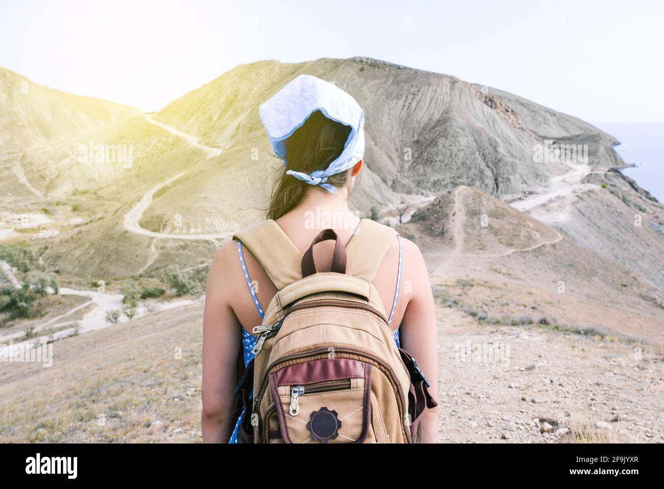 La ragazza viaggiatore con uno zaino guarda le montagne. Escursioni su sentieri di montagna. Viaggi, vacanze estive e vacanze. Foto Stock