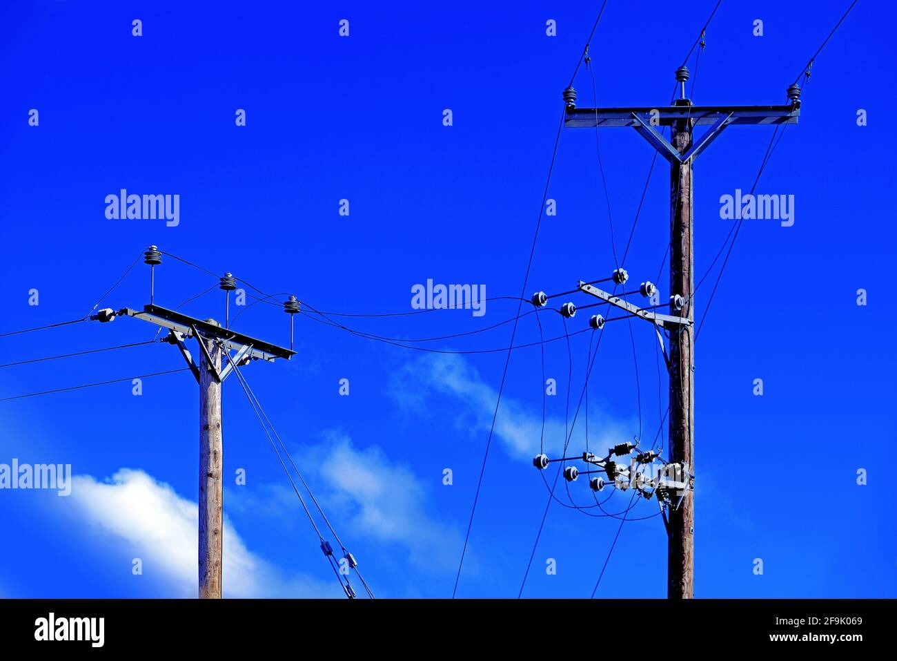 Poli telefonici cavi di linea e di alimentazione contro il cielo blu profondo Foto Stock