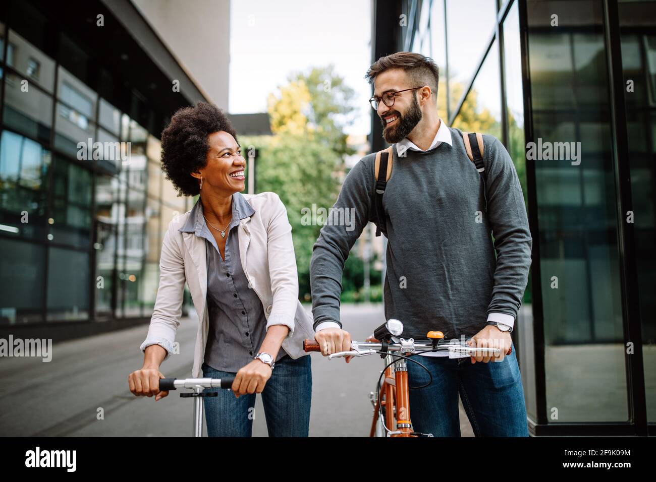Gli uomini d'affari che lavorano con la bicicletta e lo scooter elettrico su strada urbana sono felici Foto Stock