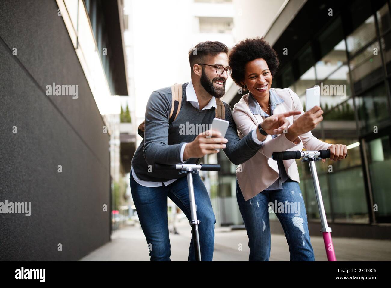 Due persone sorridenti che guidano lo scooter elettrico che vanno al lavoro. Foto Stock