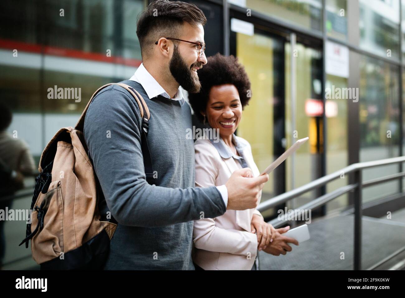 Uomini d'affari felici, studenti che si divertono, sorridono, parlano in città Foto Stock
