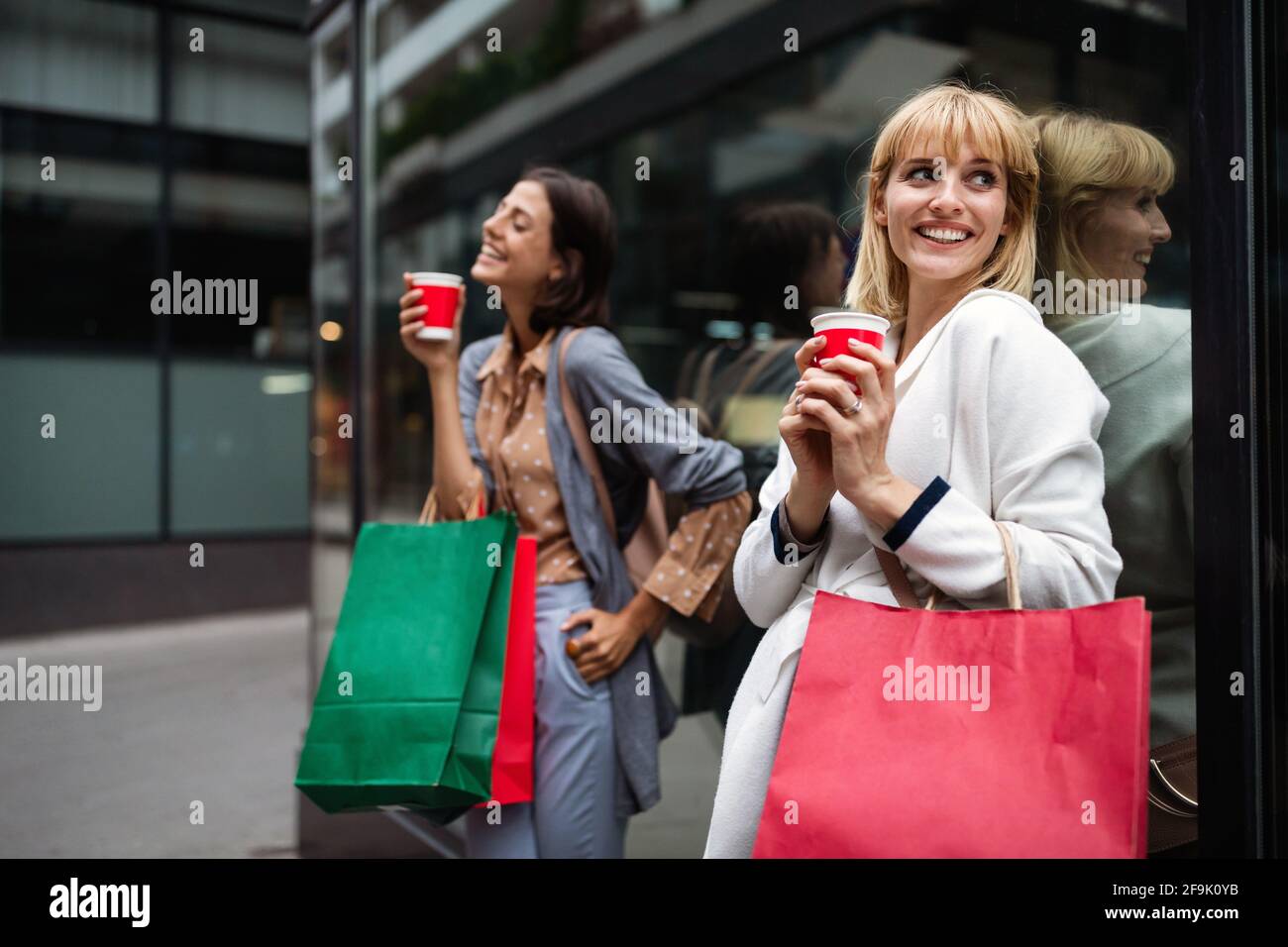 Giovani ragazze attraenti con le borse della spesa e caffè della città. Foto Stock