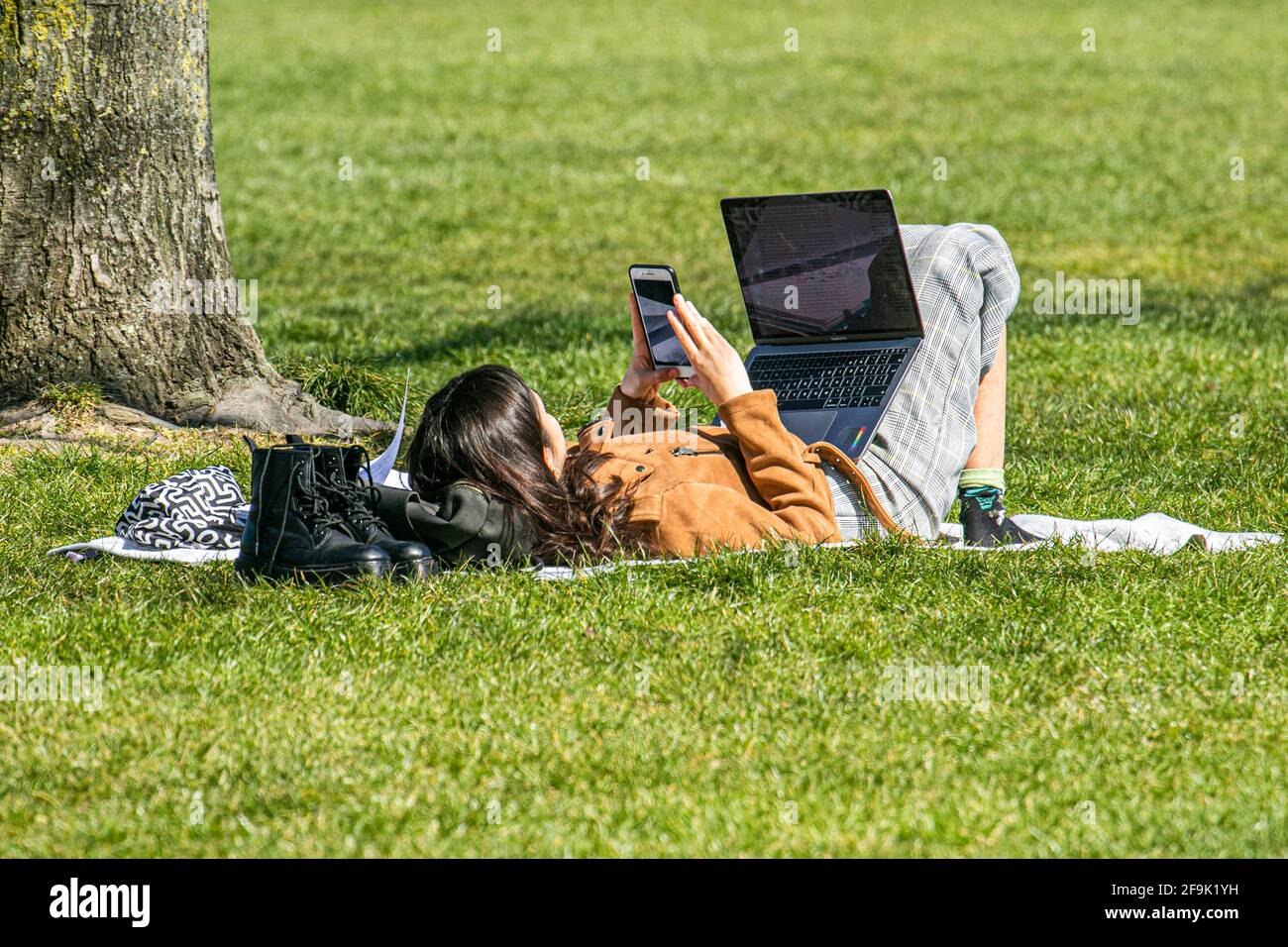 REGENT PARK LONDRA, REGNO UNITO. 19 aprile 2021. Una donna sdraiata sull'erba con un computer portatile al caldo sole di Regents Park. Una mini onda di calore ha iniziato a colpire Londra questa settimana, come le temperature più alte sono previste per raggiungere 22celsius. Credit amer Ghazzal/Alamy Live News Foto Stock