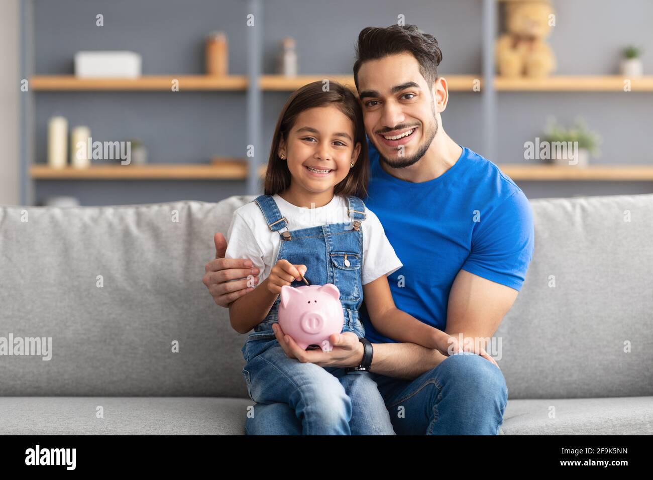 Bambina e papà risparmiando soldi in banca piggy Foto Stock