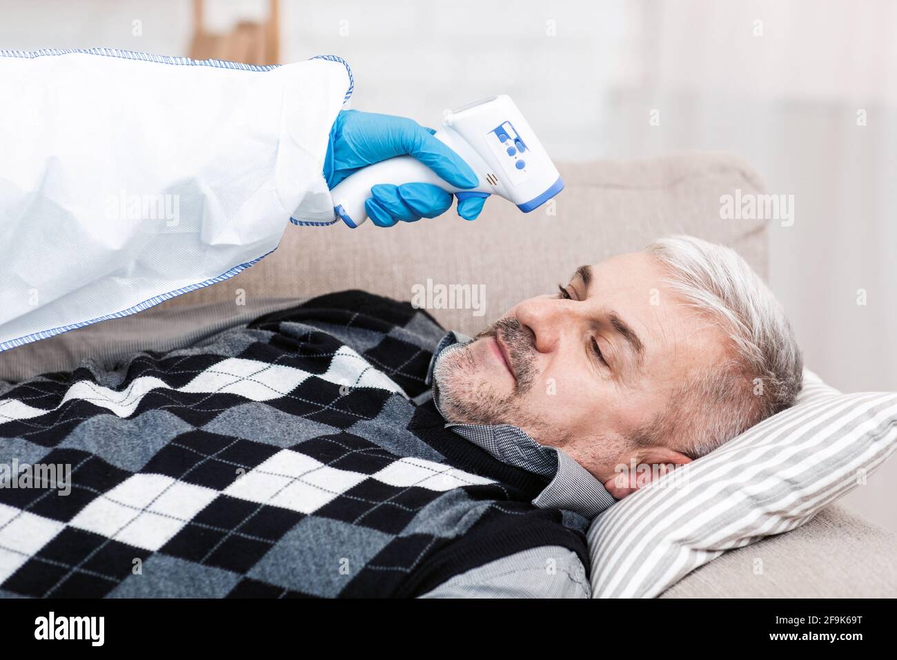 Cura del paziente durante la quarantena di covid-19, esame della persona anziana a casa Foto Stock