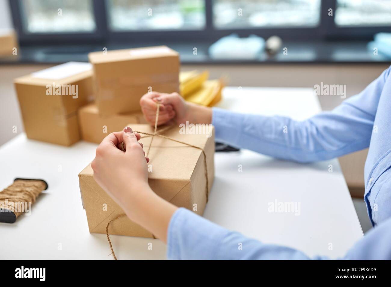 donna imballaggio pacco e corda di legatura presso l'ufficio postale Foto Stock
