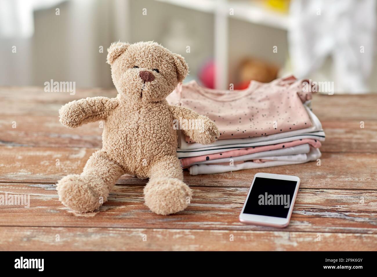 vestiti per bambini, giocattolo con orsacchiotto e smartphone Foto Stock