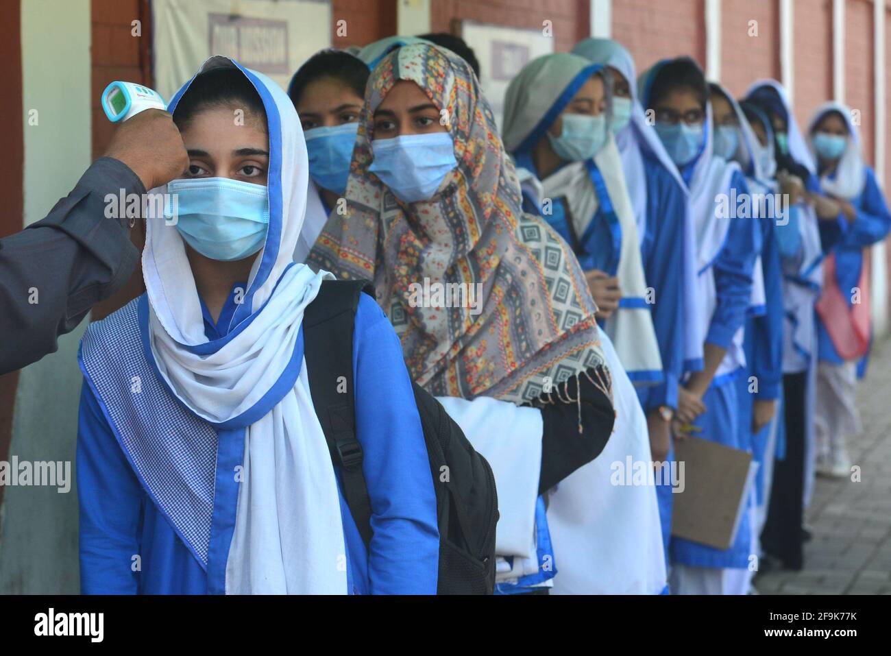 Lahore, Pakistan. 19 Apr 2021. Una guardia di sicurezza sta controllando la temperatura corporea e igienizzando le scarpe delle ragazze studentesse prima di entrare negli Istituti educativi. Governo Kinaird ragazze liceo dal 9 ° al 12 ° grado è riaperto dopo una lunga vacanza a causa della terza fase di Covid-19 a Lahore. (Foto di Rana Sajid Hussain/Pacific Press) Credit: Pacific Press Media Production Corp./Alamy Live News Foto Stock