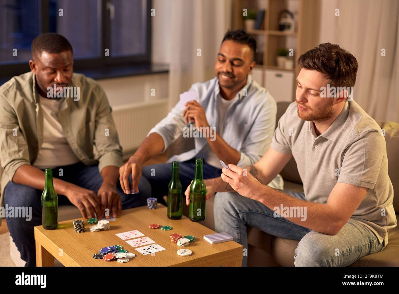 Maschio sorridente amici giocando a carte a casa Foto Stock