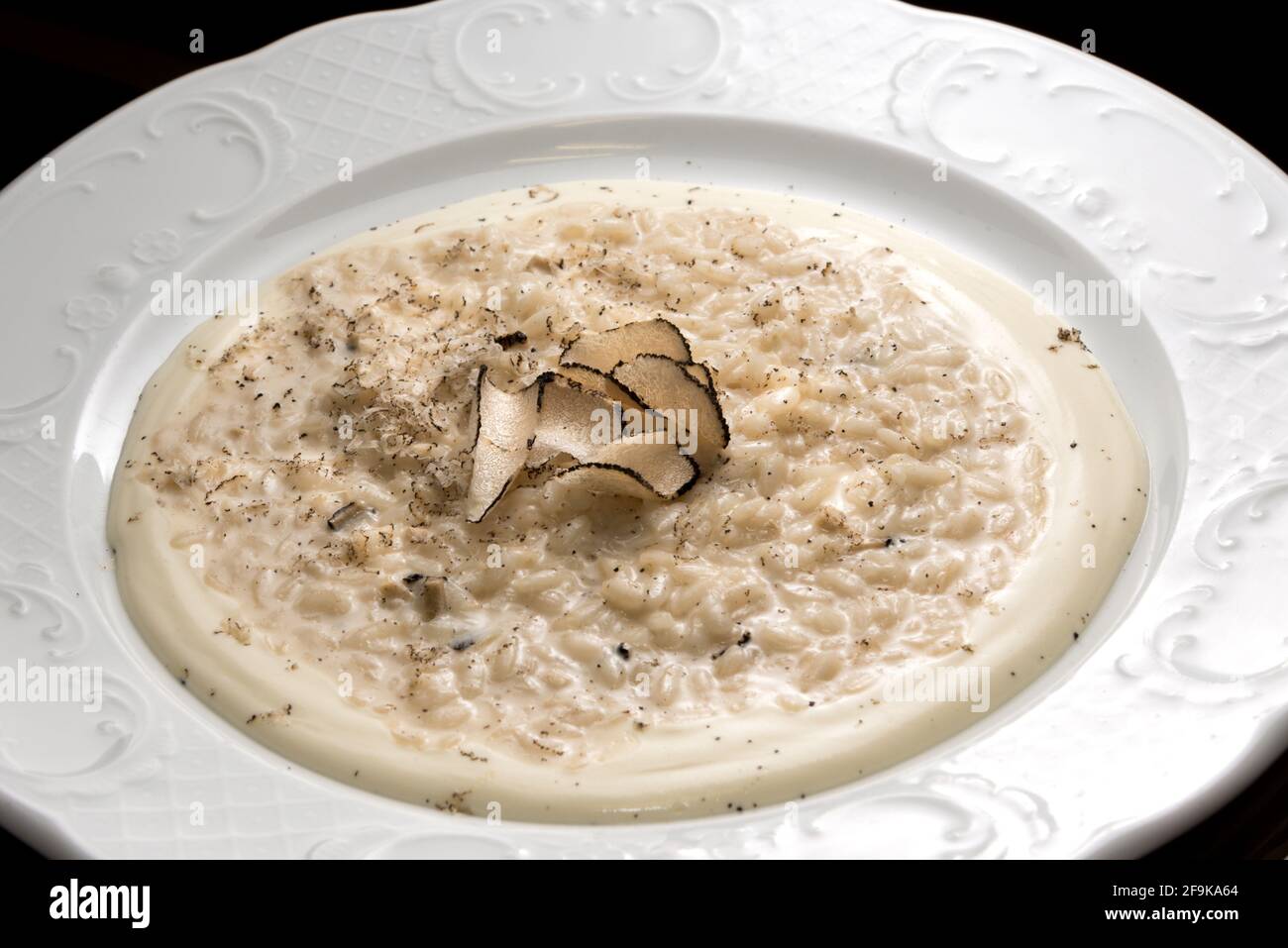 Risotto al formaggio cremoso con fettine di tartufo, in piatto bianco, primo piano Foto Stock