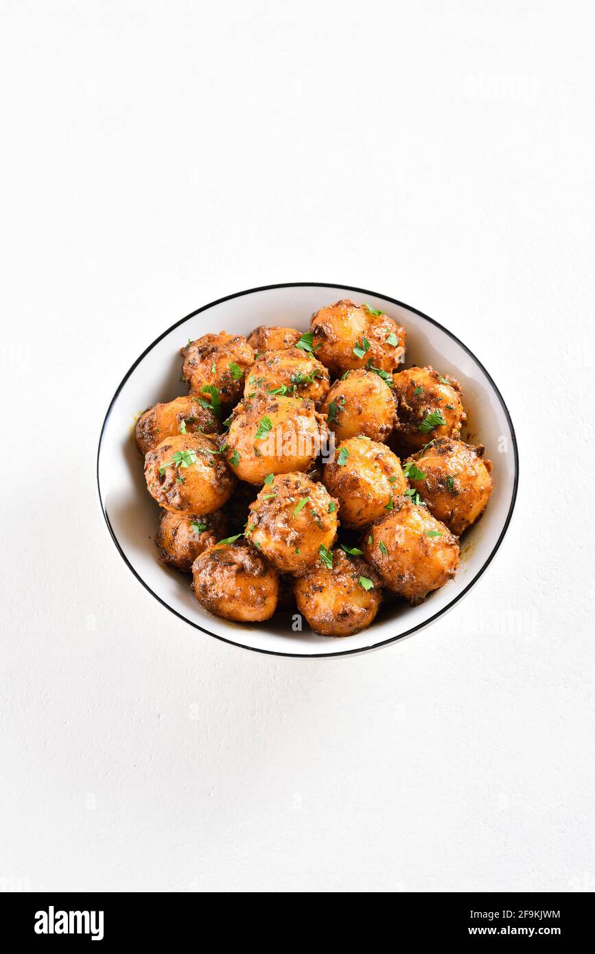 Patate Bombay. Pan patate fritte piccolo bambino con i semi di jeera e coriandolo in ciotola su sfondo chiaro con spazio libero di testo. Popolare piatto indiano. Foto Stock