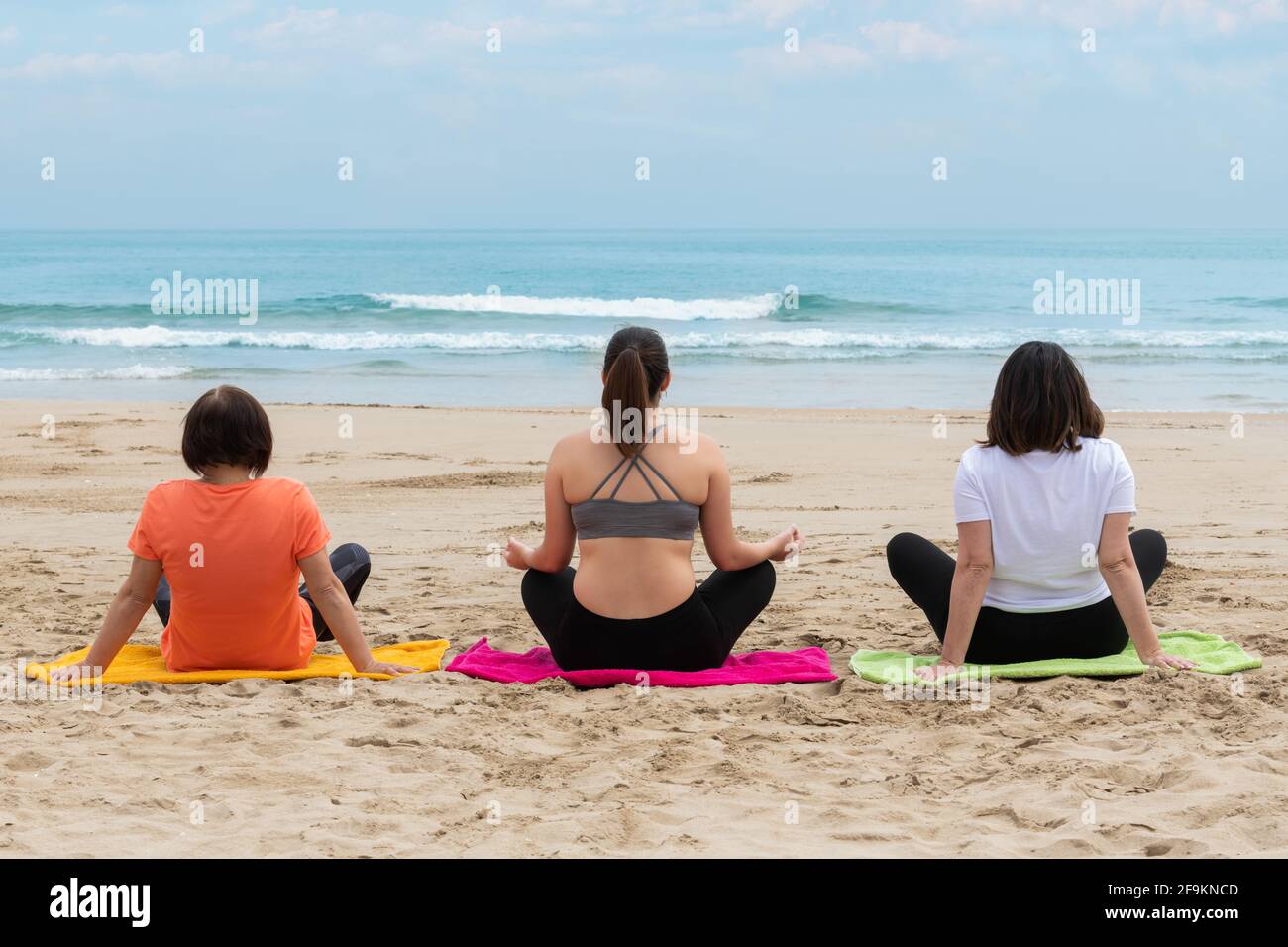 Tre donne che si rilassano e meditano in spiaggia Foto Stock