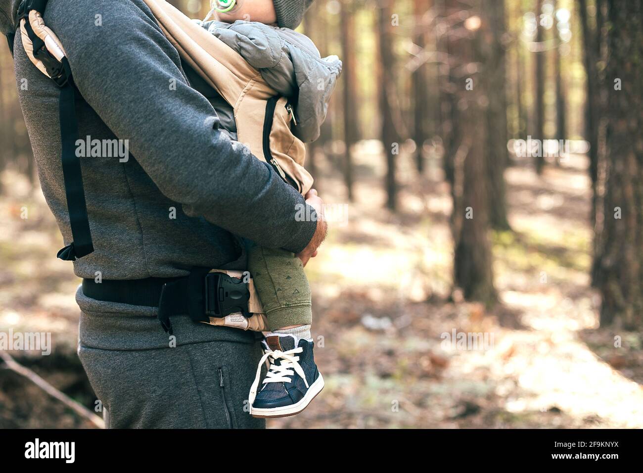 Padre che porta il suo bambino in borsa ergo. Stile di vita, momento autentico. Concetto di comunione, cura, amore dei genitori Foto Stock