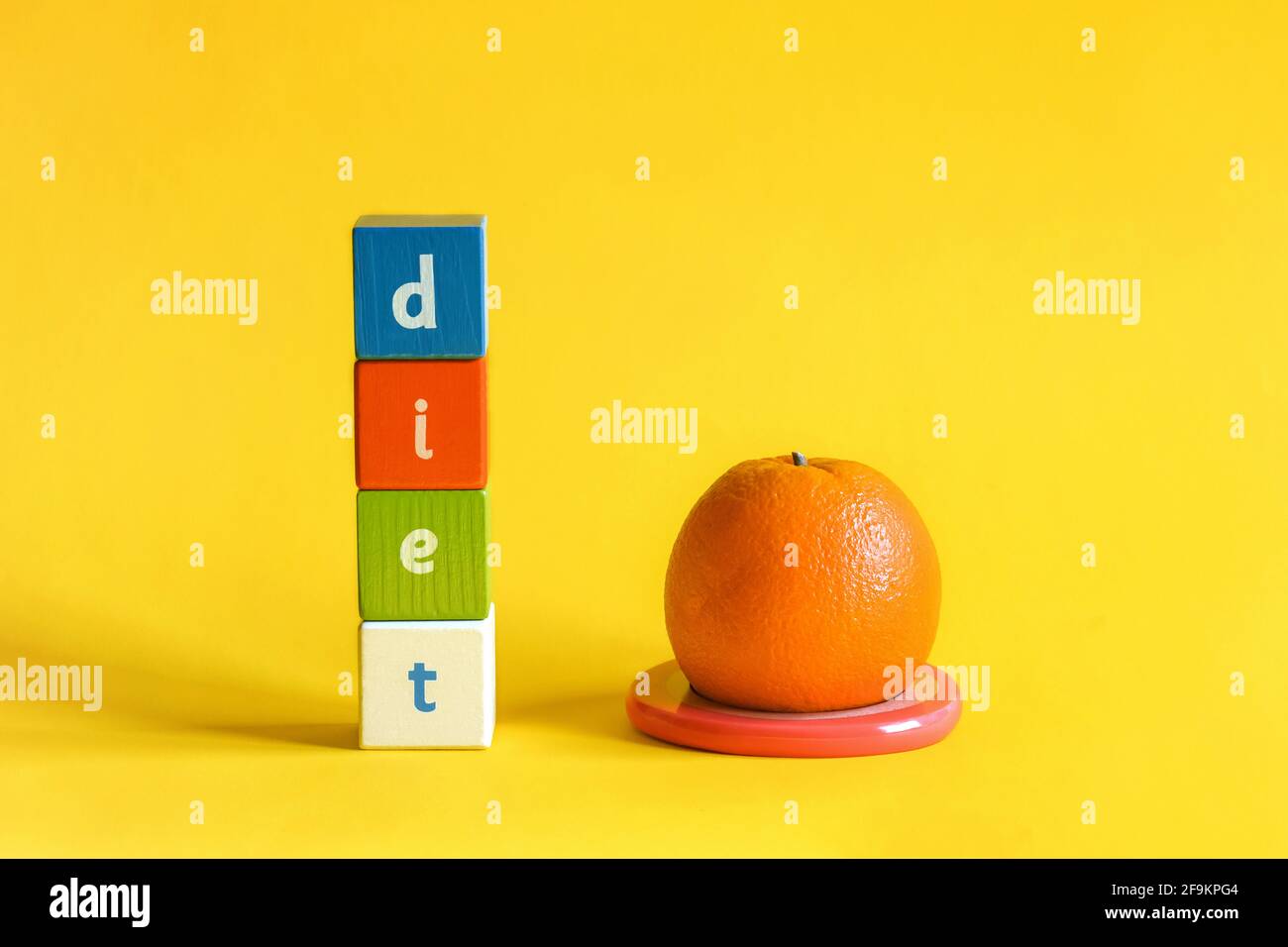 Arancione sul supporto di rosa anello di plastica e parola DIETA fatta da blocchi di legno colorati. I cubi dipinti con lettere sono disposti verticalmente Foto Stock
