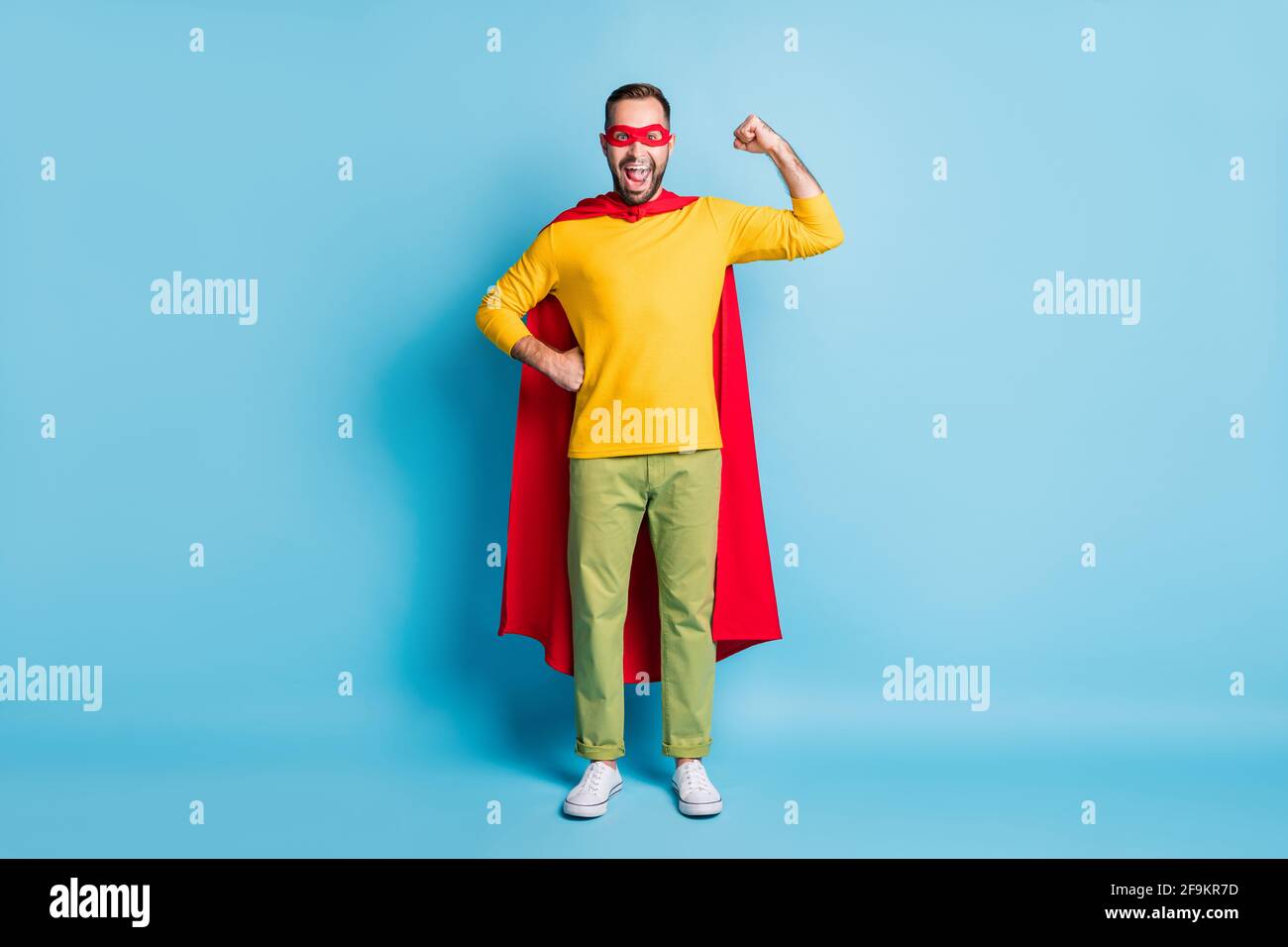 Foto a lunghezza intera delle dimensioni del corpo di un eroe che indossa una maschera in costume mostrare forti muscoli isolati su sfondo di colore blu brillante Foto Stock