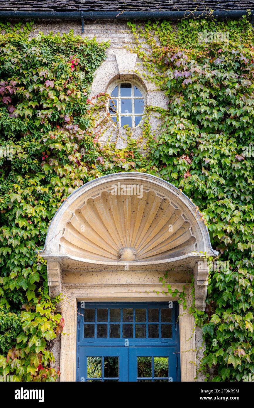 Dettaglio della porta d'ingresso blu e parete coperta di edera dello Swan Hotel, Bibury, Gloucestershire, Inghilterra, Regno Unito Foto Stock