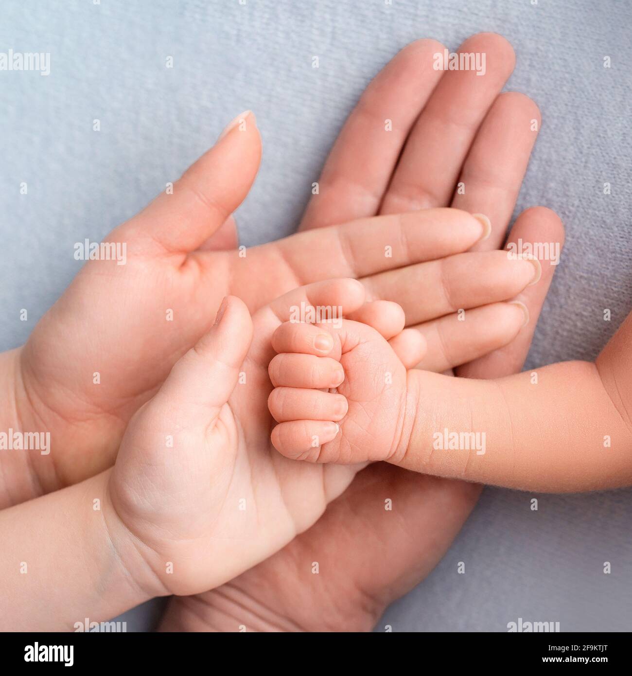 Mano del neonato. Famiglia, mamma, papà e un bambino più anziano stanno tenendo il pugno di un neonato. Foto Stock