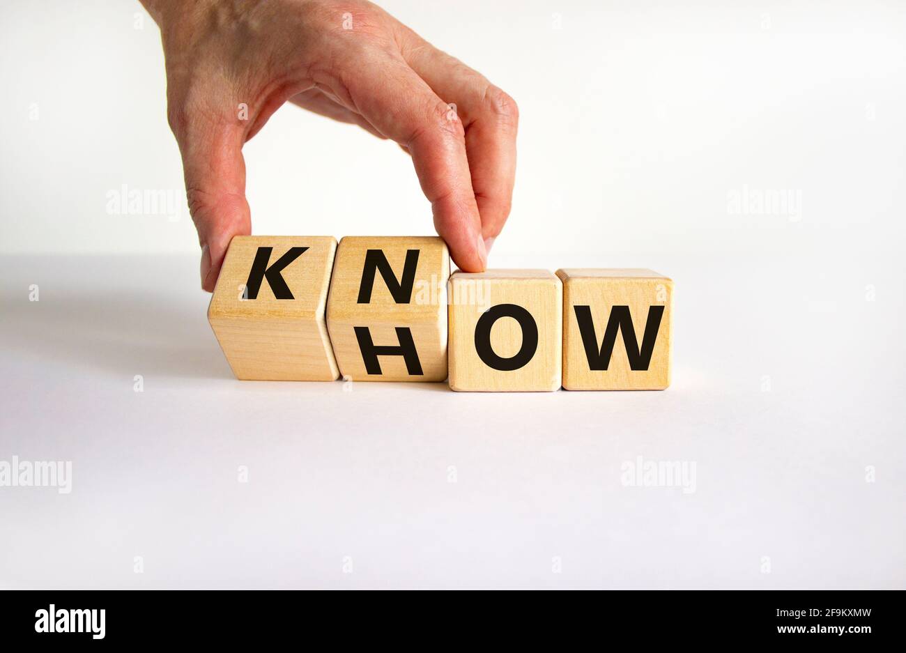 Conoscere il simbolo. L'uomo d'affari gira i cubi e cambia la parola 'come' a 'sapere'. Bel tavolo bianco, sfondo bianco. Spazio di copia. Business e know Foto Stock