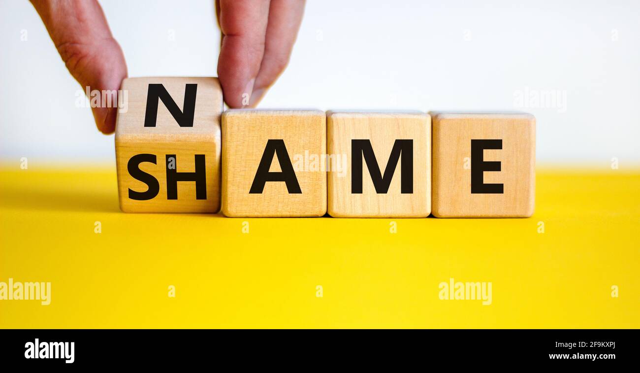 Nome o simbolo di vergogna. Uomo d'affari trasforma il cubo di legno e cambia la parola 'nome' in 'nome' o viceversa. Bel tavolo giallo, sfondo bianco Foto Stock