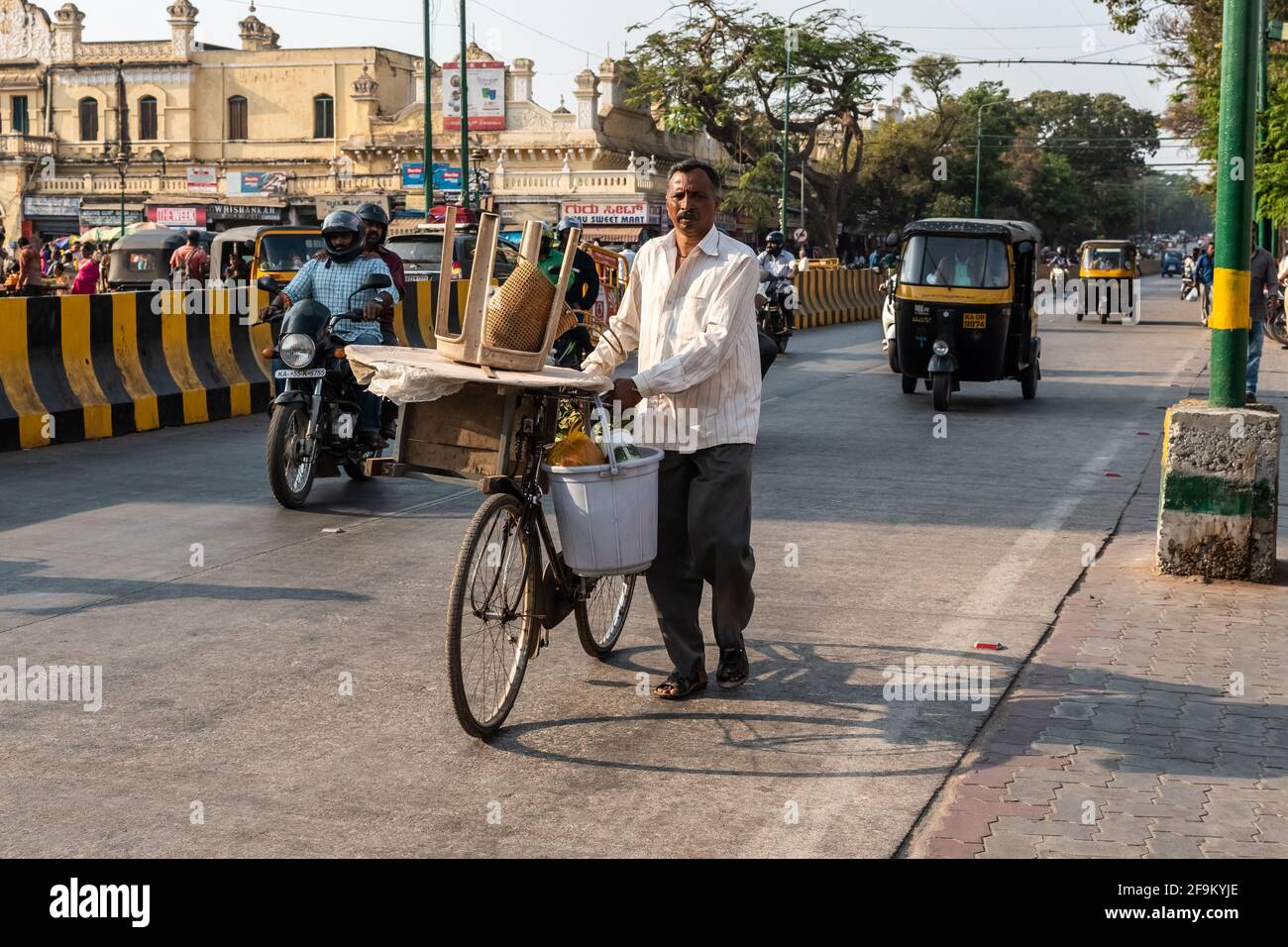 Mysuru, Karnataka, India - Gennaio 2019: Un venditore di strada che cammina con la sua bicicletta su una strada trafficata nella città di Mysore. Foto Stock