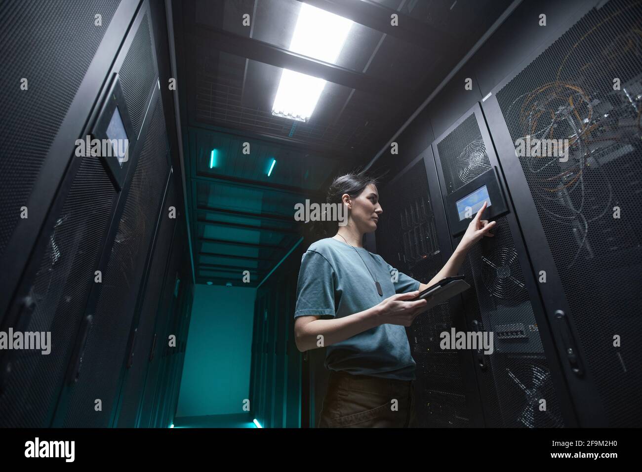 Ritratto a basso angolo di donna militare utilizzando il pannello di controllo durante la configurazione dei server nel data center, spazio di copia Foto Stock