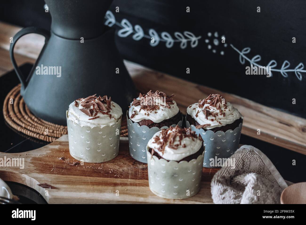 muffin al cioccolato con crema cremosa al formaggio e cioccolato schegge spruzzate su sfondo nero Foto Stock