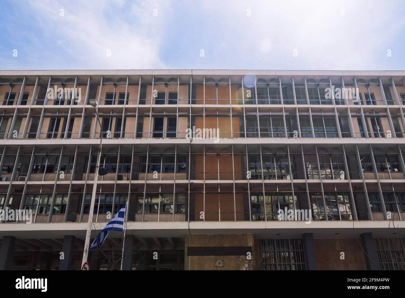 Salonicco, Grecia facciata del tribunale con bandiera ellenica che sventola. Esterno giorno vista ad angolo basso dei tribunali della giustizia edificio con segno. Foto Stock