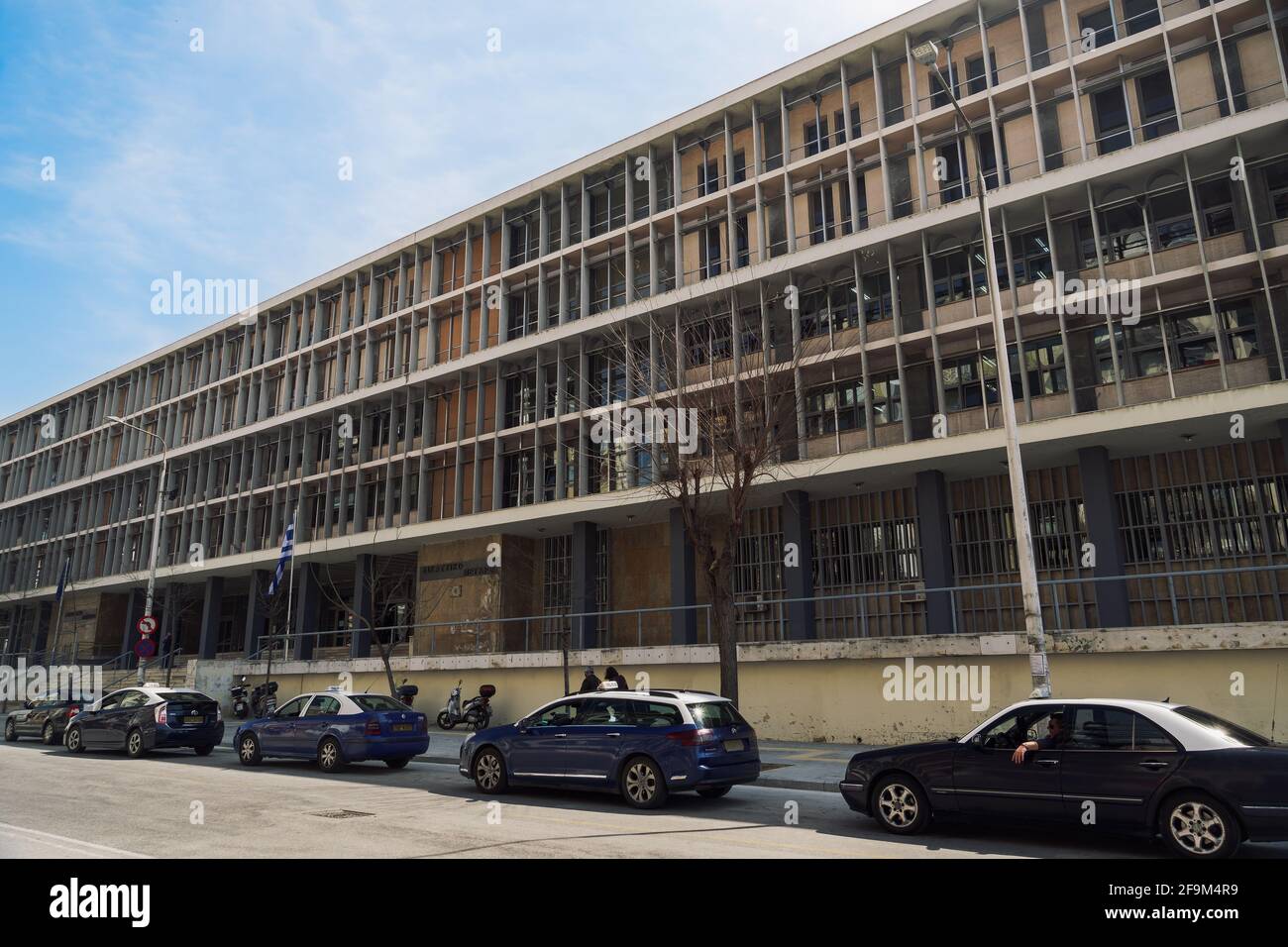 Salonicco, Grecia facciata del tribunale con bandiera ellenica che sventola. Esterno giorno vista ad angolo basso dei tribunali della giustizia edificio con segno e taxi parcheggiati Foto Stock