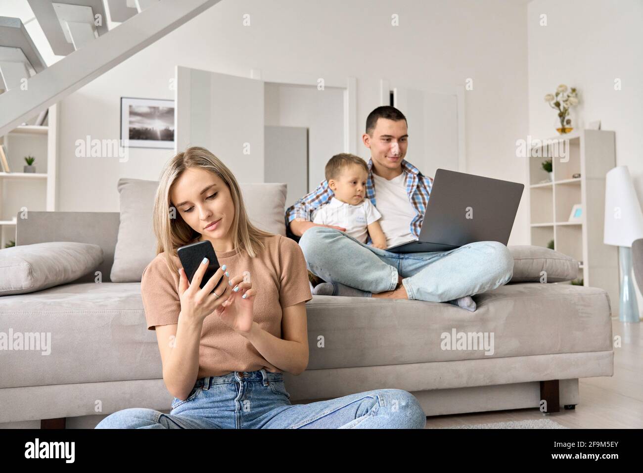 Giovane famiglia con bambino a casa guardando film online, navigando sui social media. Foto Stock
