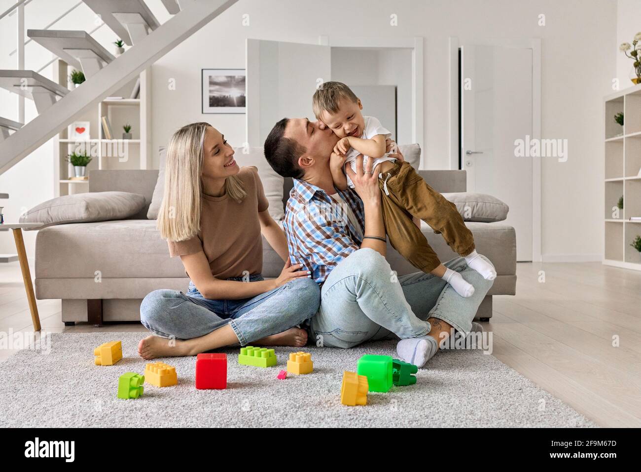 Felice giovane famiglia con bambino bambino seduto sul pavimento in soggiorno moderno. Foto Stock