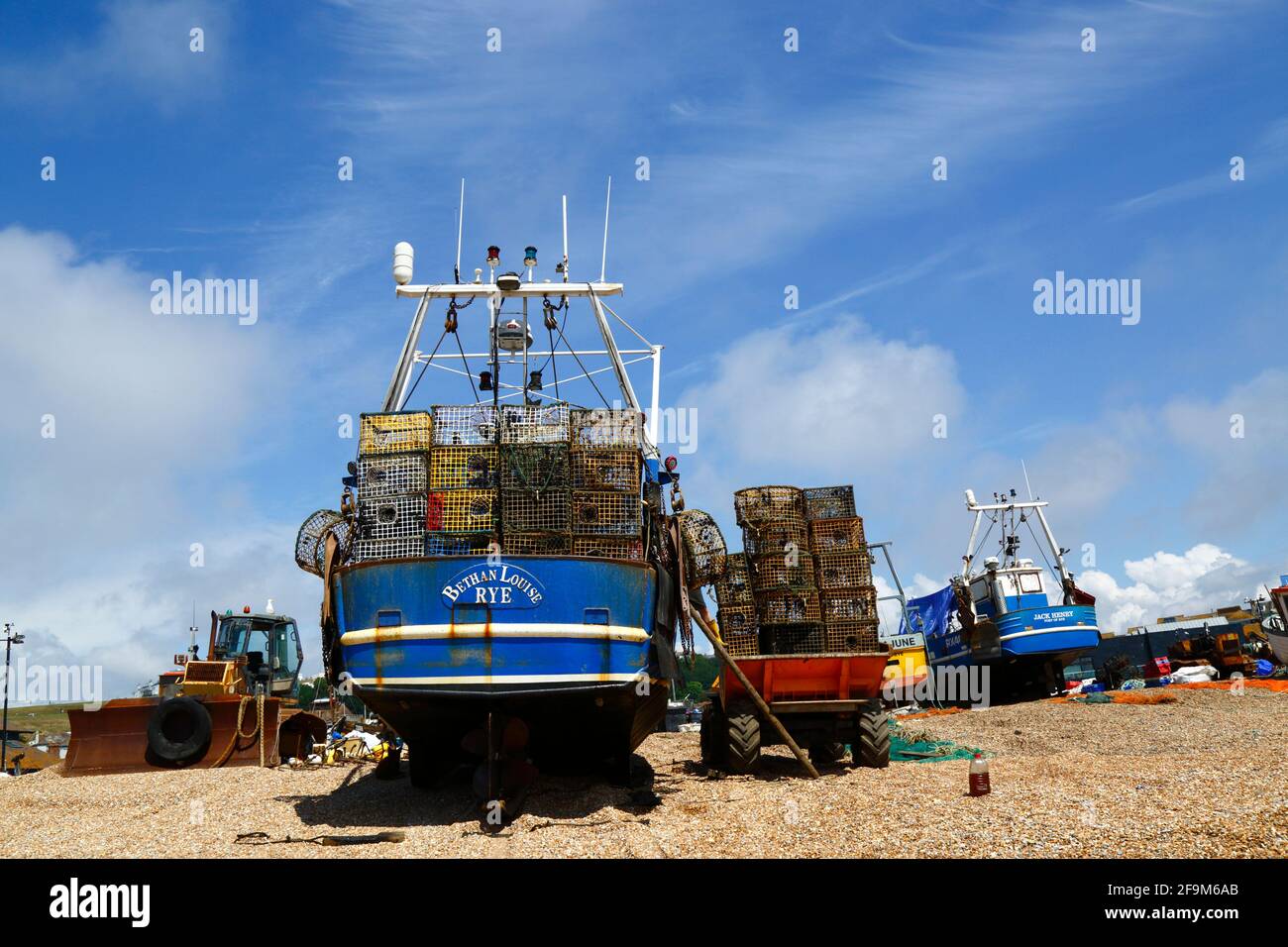 Barca da pesca con pile di trappole di granchio sul ponte sulla spiaggia di stade Shingle, Hastings, East Sussex, Inghilterra, Regno Unito Foto Stock