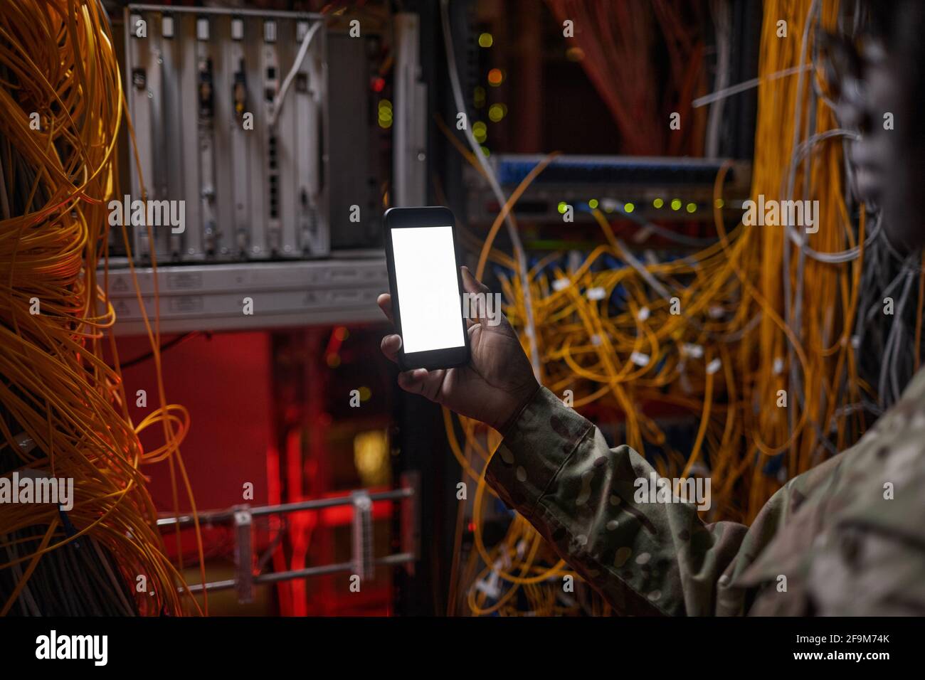 Primo piano di una donna irriconoscibile che tiene uno smartphone con schermo vuoto durante l'ispezione del server, spazio di copia Foto Stock