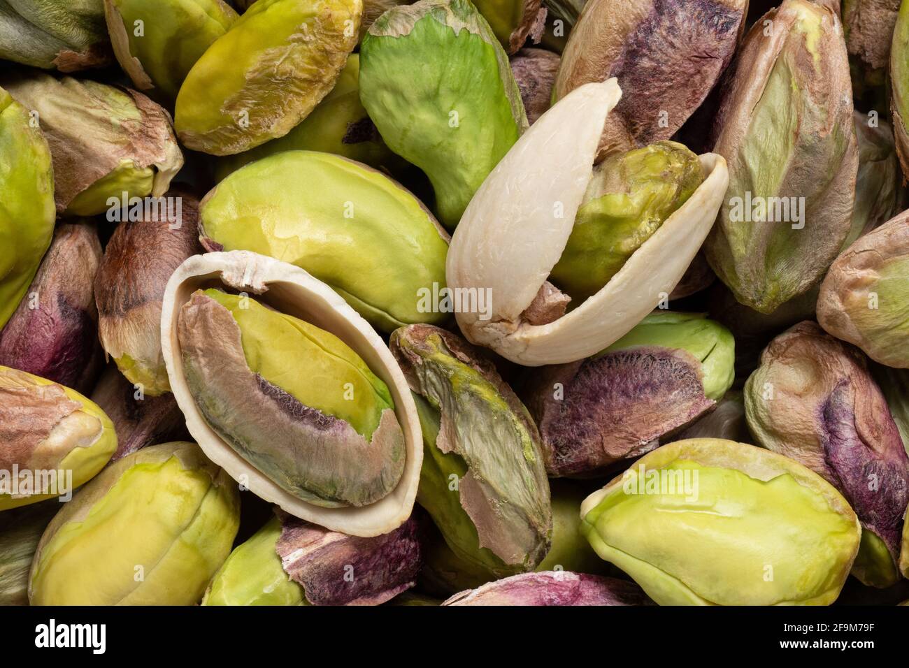Sfondo di pistacchi sgusciati e due pistacchi aperti. Vista dall'alto. Foto Stock