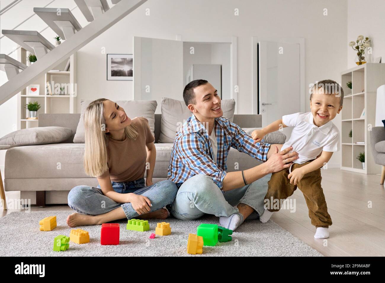 Felice giovane coppia di famiglia che si diverte a giocare con cute bambino figlio a casa. Foto Stock