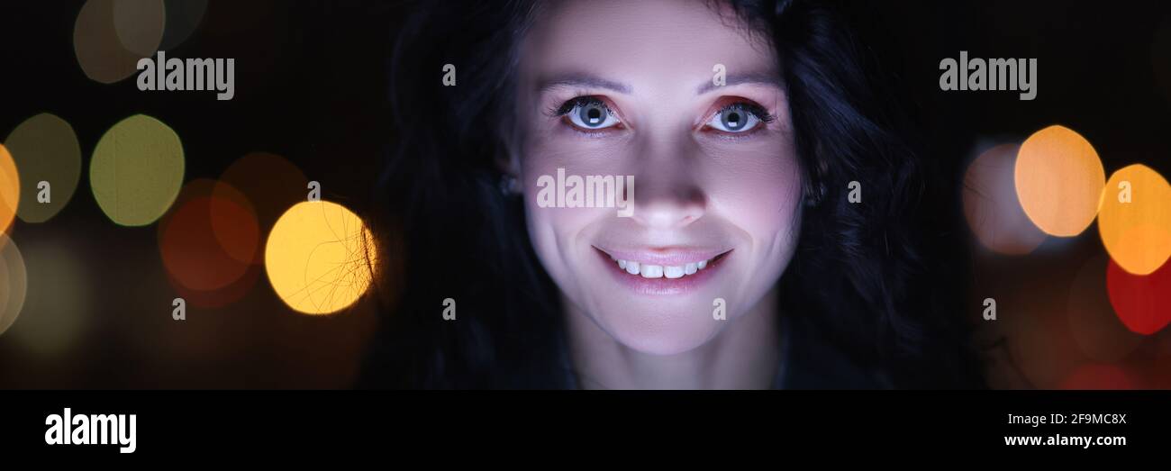 Ritratto di donna brunetta al computer portatile di notte sullo sfondo di ghirlande Foto Stock