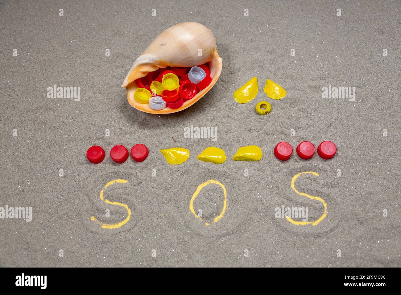 SOS realizzato in tappi per bottiglie in plastica PET e conchiglie. Allarme inquinamento della natura. Foto Stock