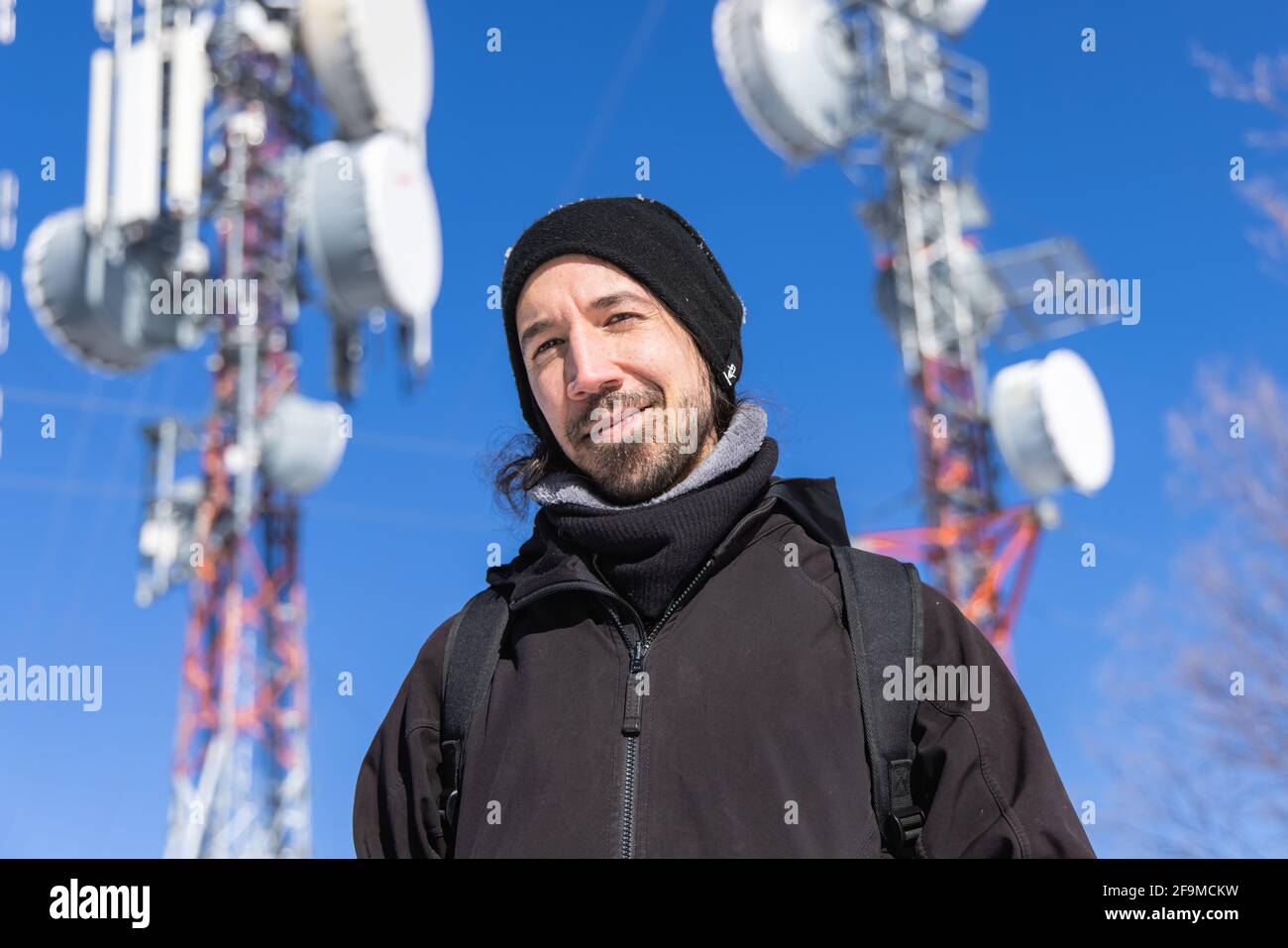 Una foto super chiara di un visitatore che si trova di fronte alle torri base cellulari, con diverse antenne, che forniscono servizi mobili 3G e 4G Foto Stock