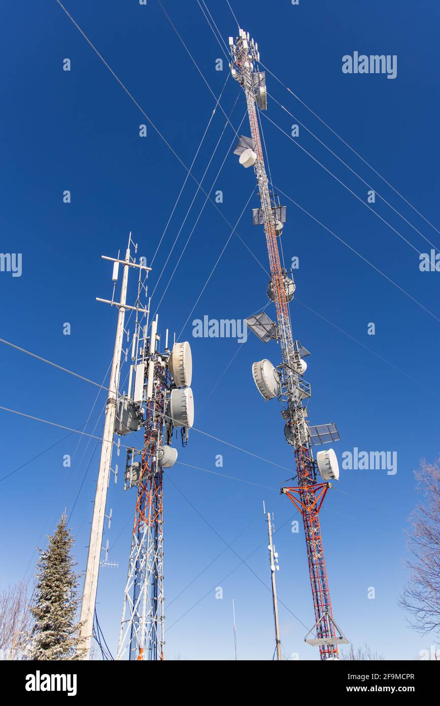 Fotografia professionale di due torri di telecomunicazione 3G e 4G, con antenne collegate, ripetitori di rete e vari cavi interconnessi. Foto Stock