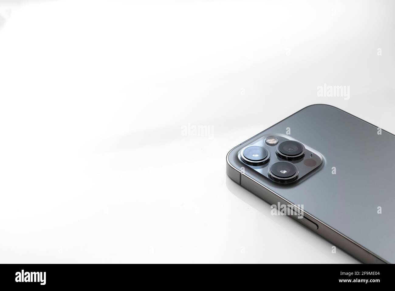 Dettaglio di un Apple iPhone 12 Pro Max rivolto verso il basso su uno sfondo fiancheggiato con spazio per la copia, mostrando i suoi tre obiettivi della fotocamera, orizzontale Foto Stock