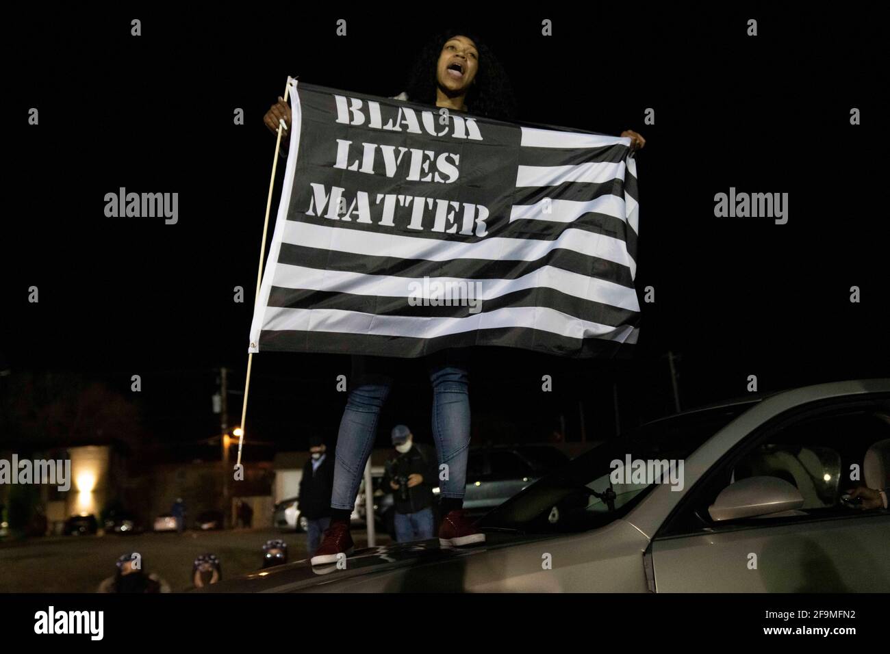 Brooklyn Center, Minnesota, Stati Uniti. 17 Apr 2021. Un protester fa ondere una Black Lives Matter Flag in cima a un'auto fuori dal Brooklyn Center Police Department. Le proteste continuarono per la settima notte consecutiva fuori dal Dipartimento di polizia del Brooklyn Center dopo che l'ex ufficiale Kim Porter uccise Daunte Wright, 20 anni, in una fermata del traffico. Credit: Dominick Sokotoff/ZUMA Wire/Alamy Live News Foto Stock