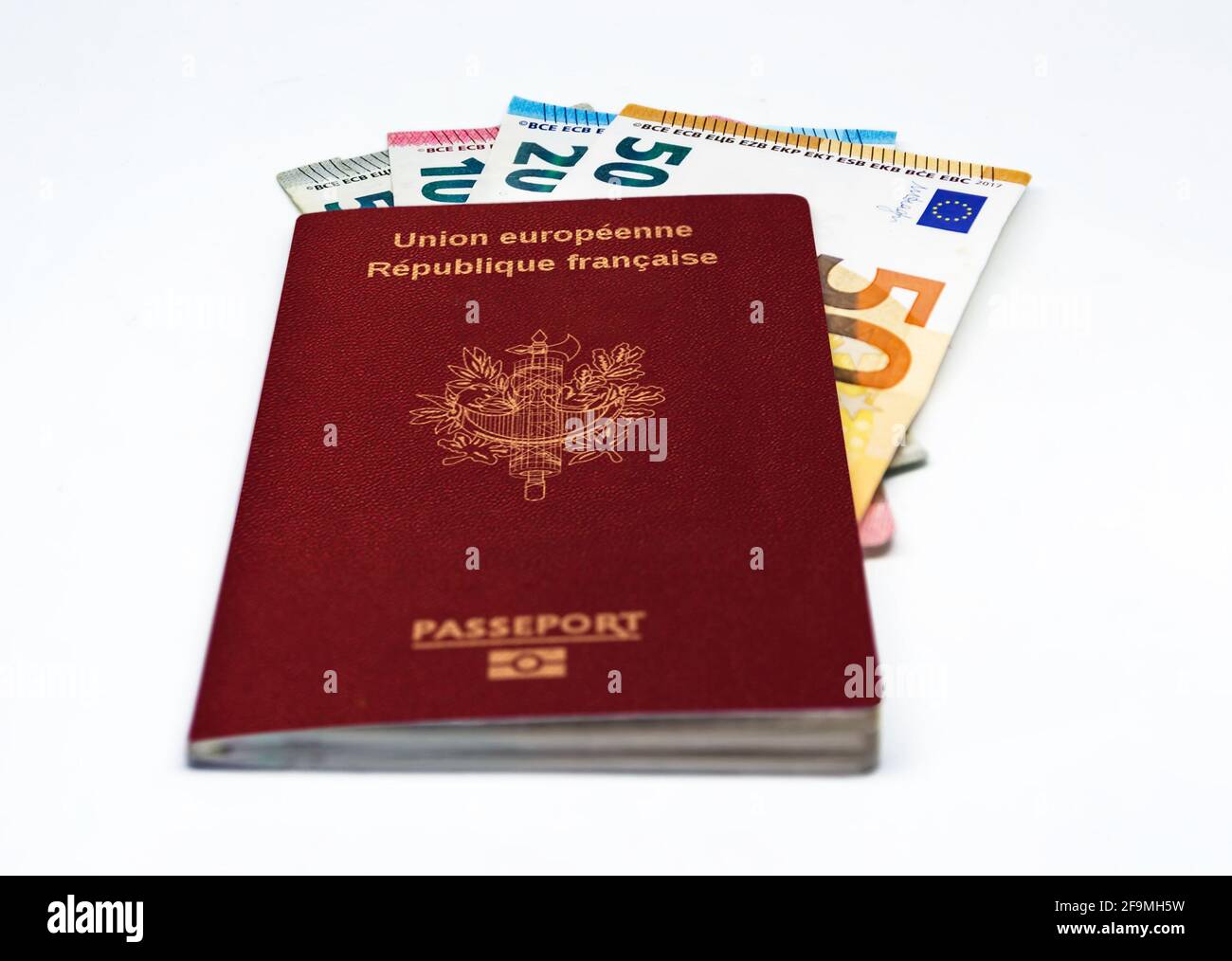 Passaporto francese di viaggio con alcune banconote in euro isolate su sfondo bianco. Unione europea e moneta unica. Viaggi e contanti Foto Stock