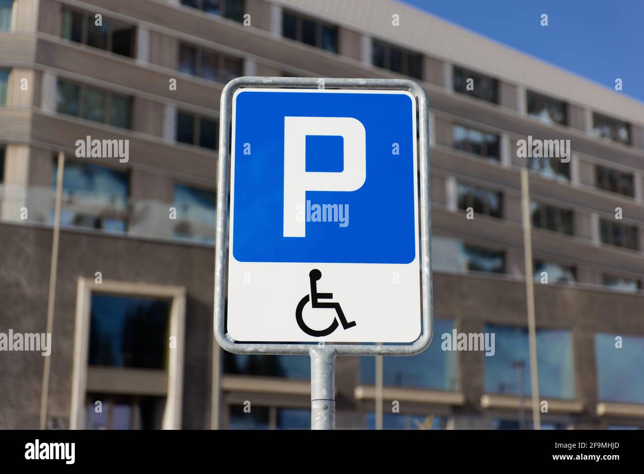 cartello stradale blu con simbolo della sedia a rotelle, parcheggio per disabili, solo le persone autorizzate con un documento d'identità valido possono parcheggiare qui, di giorno, con carta di identità Foto Stock