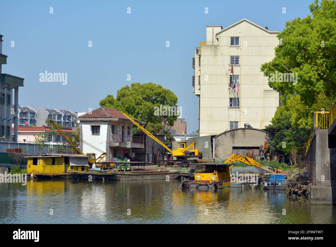 Lavori di costruzione sul bordo del Canal Grande di Jiaxing, gru gialle sia per l'uso della terra che dell'acqua. Foto Stock